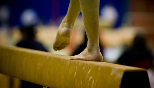 girl balances on gymnastics balance beam