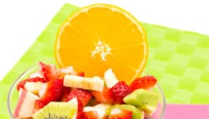 Close up of a coloful bowl of fruit salad with a big orange slice as a centerpiece