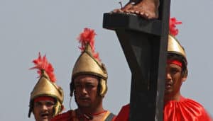 Three men costumed as Roman soldiers standing at the foot of the Cross at a re-enactment of the Crucifixion.