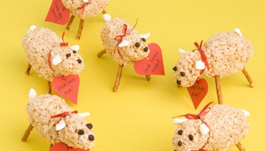 Rice Krispie treats shaped like sheep with pretzel stick legs. Each has heart-shaped sign on its neck saying "God loves ewe!"