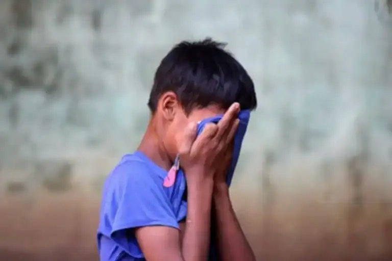 Boy covering his eyes with hands and cloth, representing sensory processing issues in children.