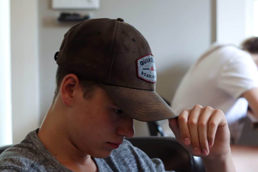 Teen boy with hat looking down