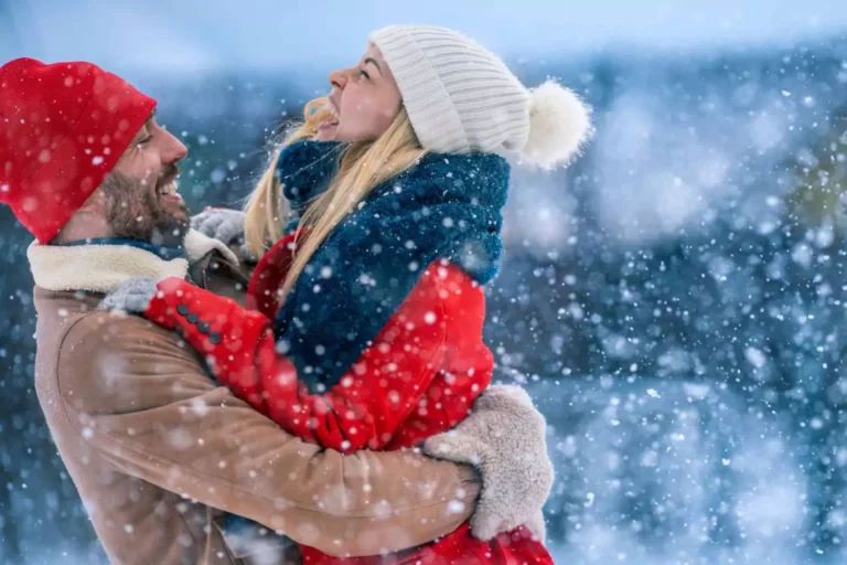 A couple embraces joyfully in a snowy landscape, representing the best Christmas gift is love and togetherness as a couple.