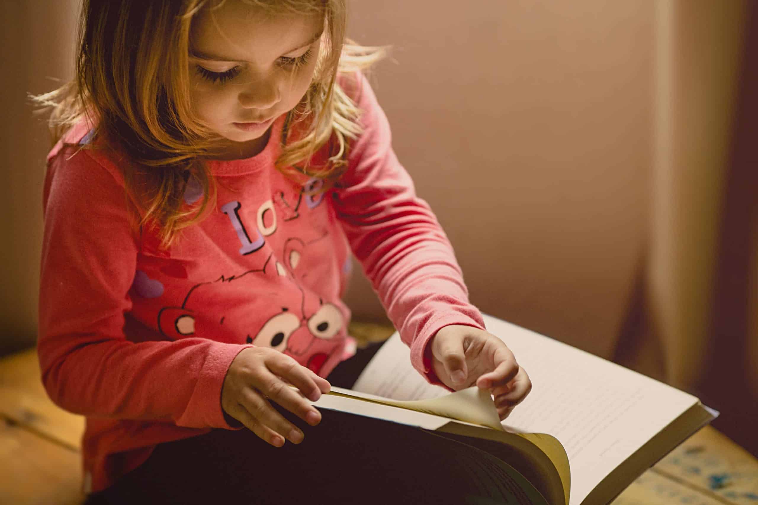 Young girl sitting on her bed flipping through a book