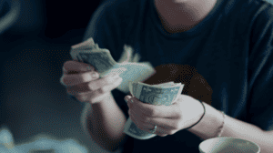 Close up of a woman's hands counting a stack of one dollar bills