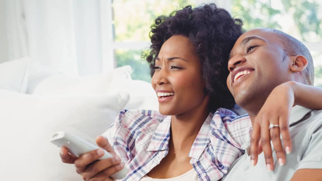 A couple laughs while watching TV