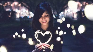 Older girl smiles as she holds an illuminated heart