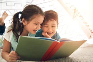 2 young children learning together by reading a book