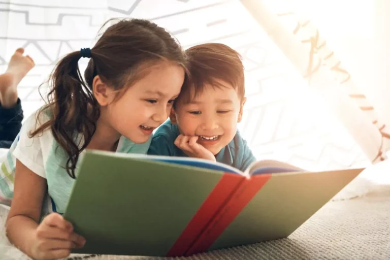 2 young children learning together by reading a book