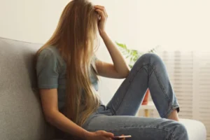 woman sitting against the wall with her hand to her head, discouraged about her spouse wanting a divorce, when she doesn't want to divorce him.