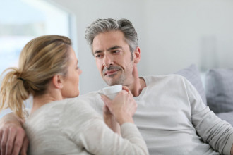 Middle age couple sitting on their couch, having a serious conversation