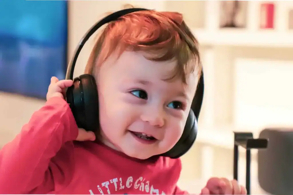 Smiling toddler wearing headphones, exploring auditory learning through sound and music.