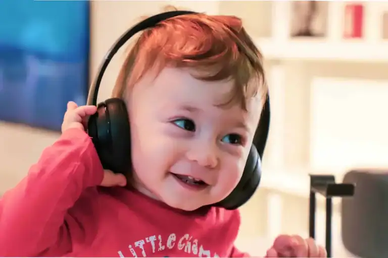 Smiling toddler wearing headphones, exploring auditory learning through sound and music.