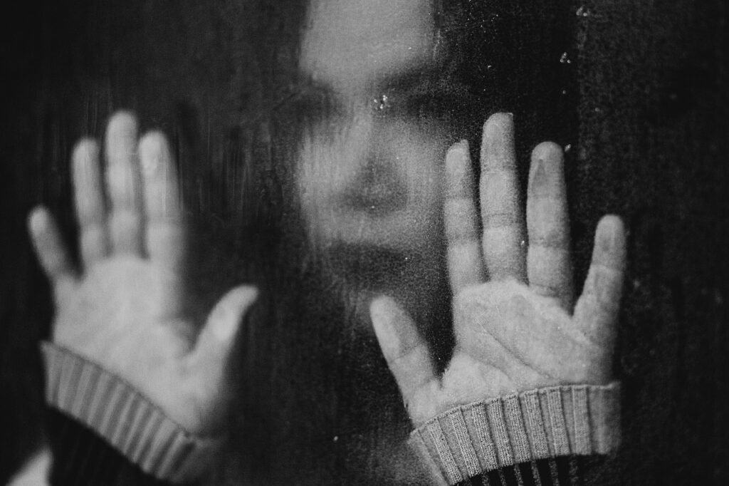 Black and white pic of woman stuck behind a glass pane.