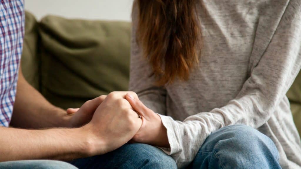 Close up of couple holding hands working through worry and stress