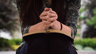Woman prays with Bible on her lap