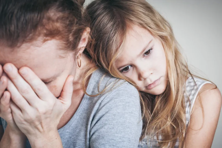 Sad young girl leaning on the shoulder of a distressed woman covering her face with her hands.