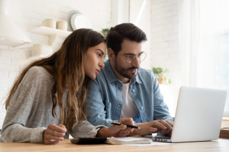 a man and woman look at a computer