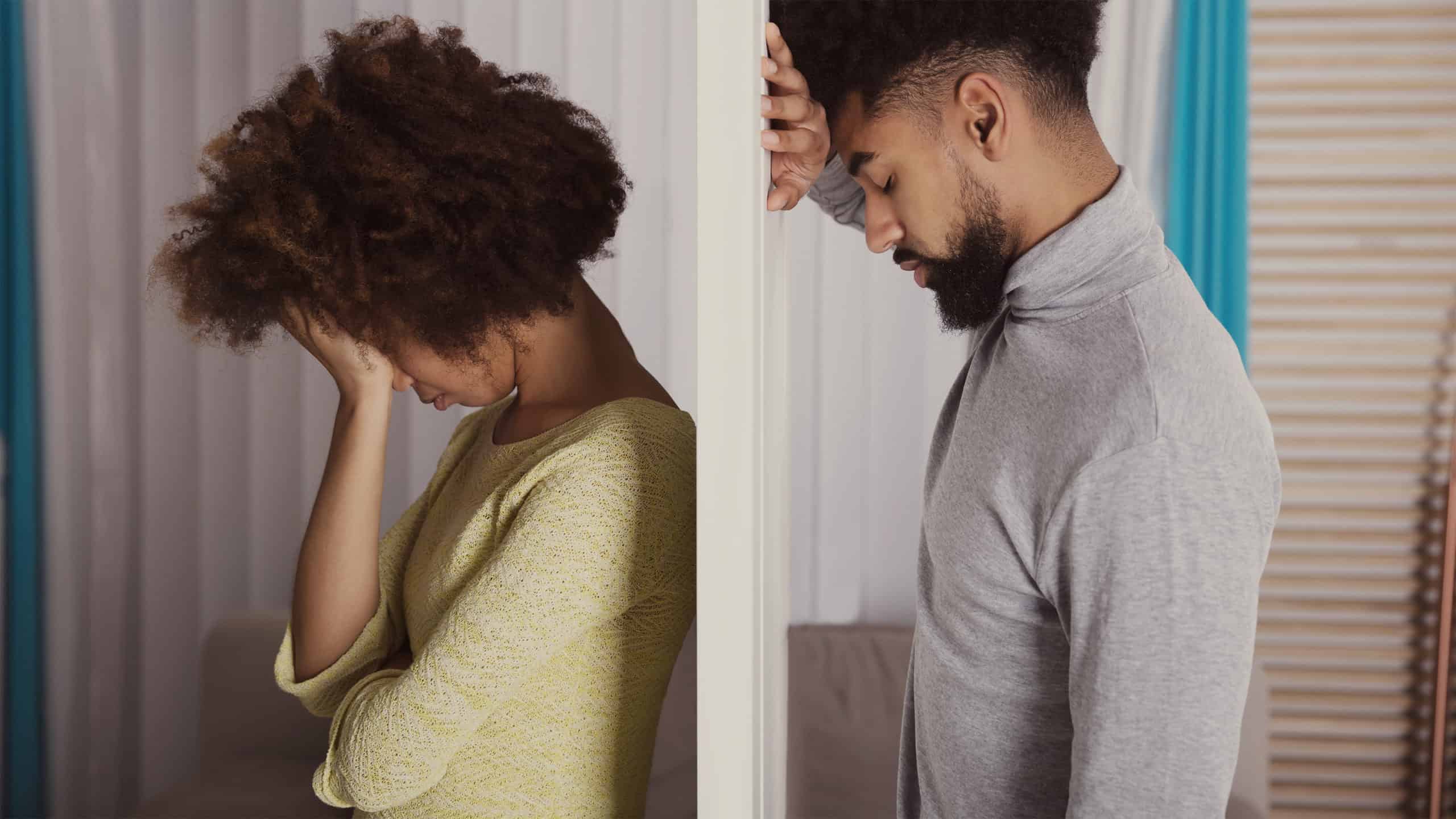 Profile shot of depressed-looking black couple separated by a wall, with each leaning against it from their respective side