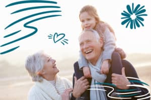 Happy grandparents outside with their young granddaughter. Grandpa is giving the girl a piggyback ride on his shoulders.