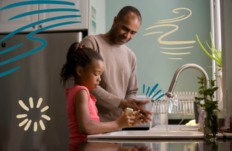 Close up of dad and young daughter washing their hands at the kitchen sink