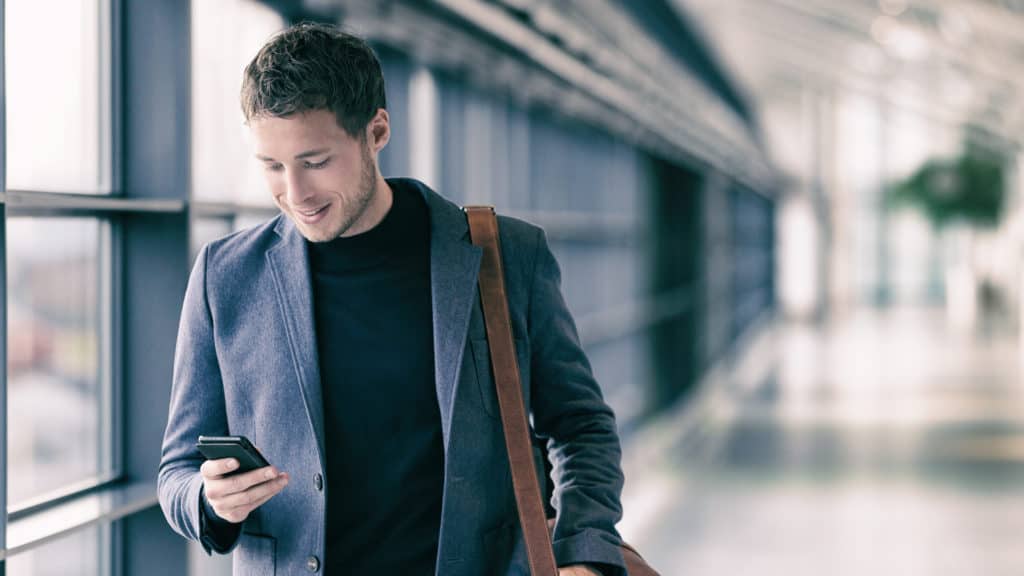 a man checks his phone while walking throug an airport