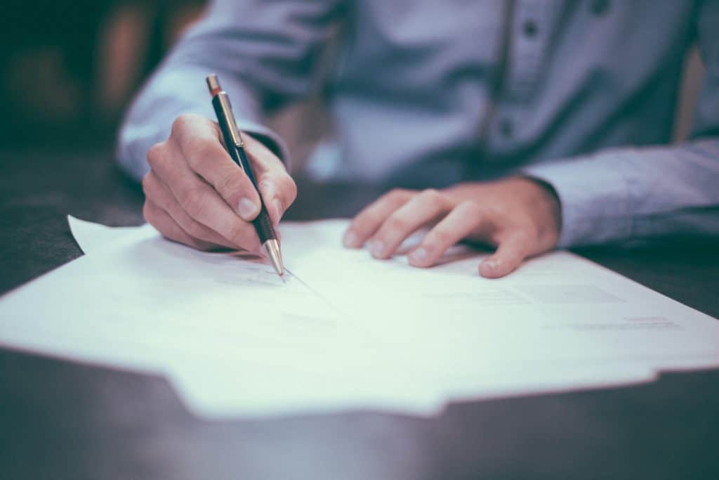 Close up of a man's hands writing on some documents