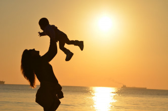 Woman lifting child with sunset