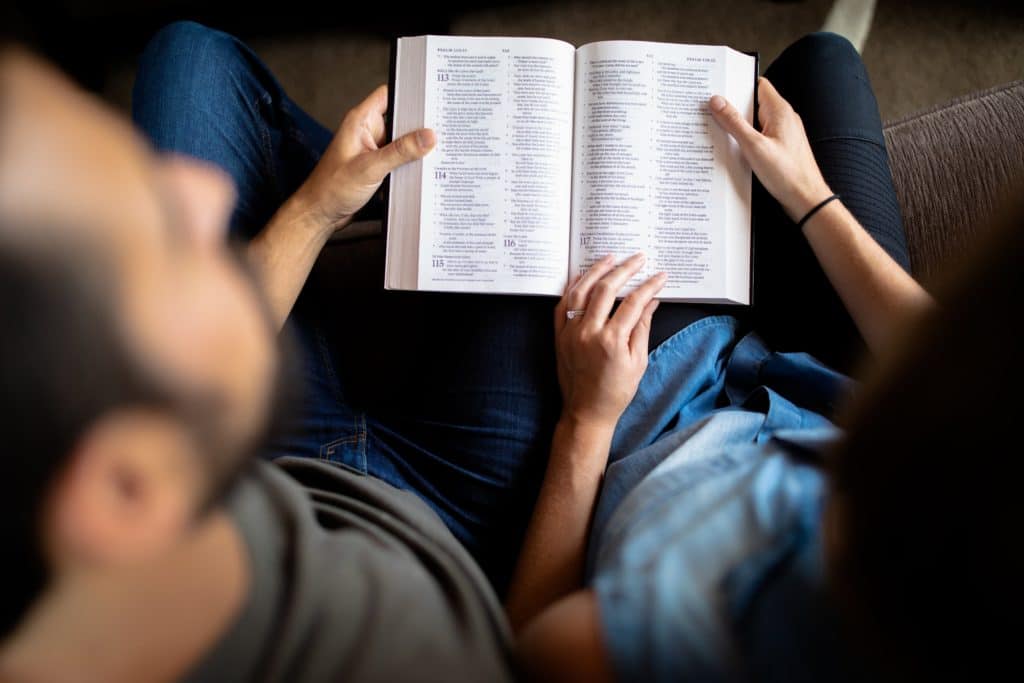 Married couple reading Bible together on couch