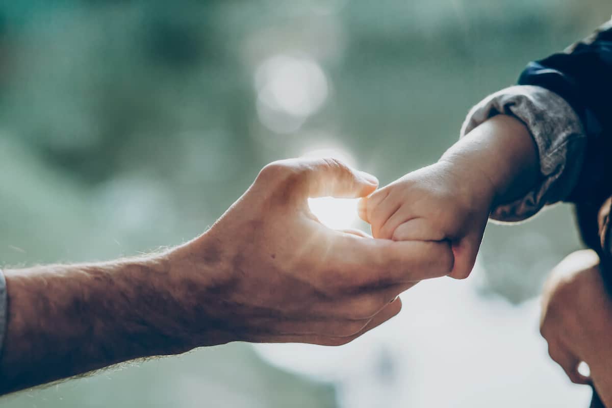 father and little son holding hands in sunlight.