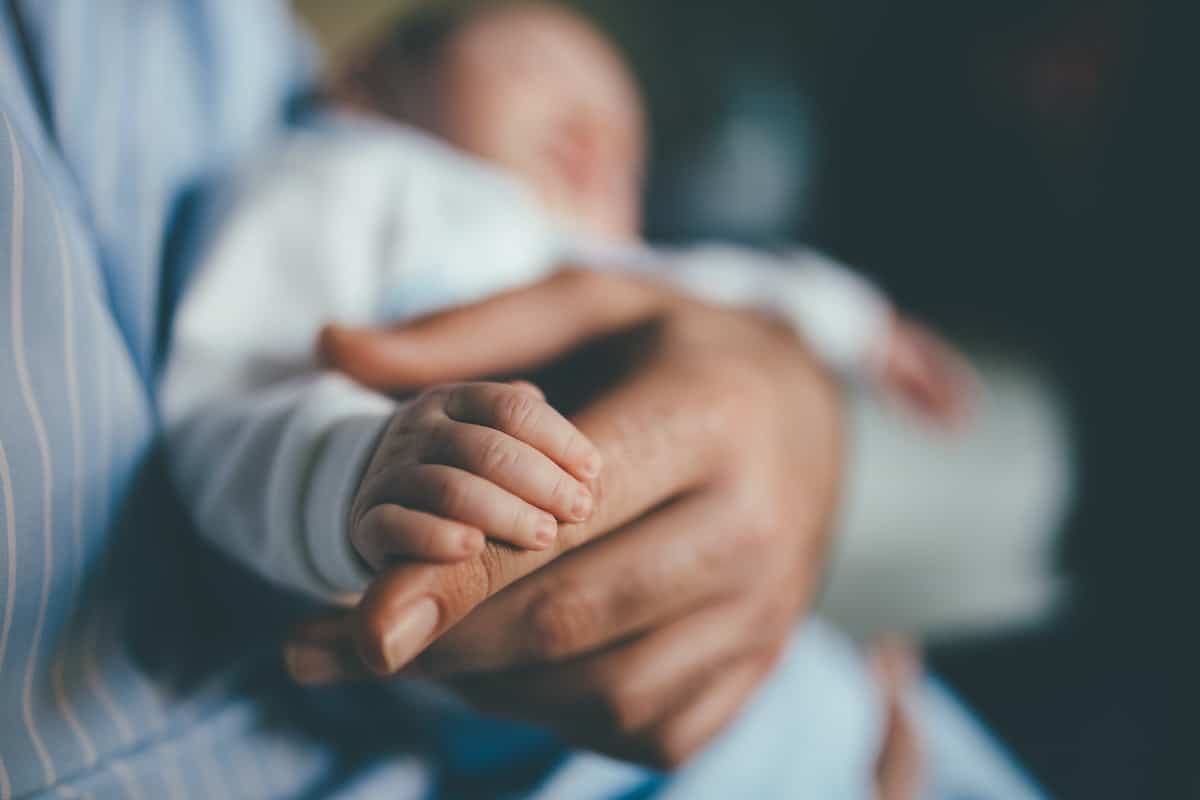 A baby holds his father's hand