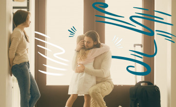 Father who is leaving for a trip kneeling down to hug his young daughter while mom looks on.