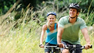 A man and woman ride bikes in a grassy area