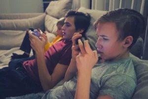 Three boys on cellphones sitting on the couch