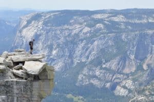 picture of a hiker standing high on rock cliff