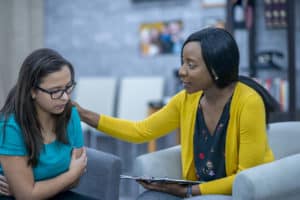 A sad teen girl being counseled by an encouraging caseworker