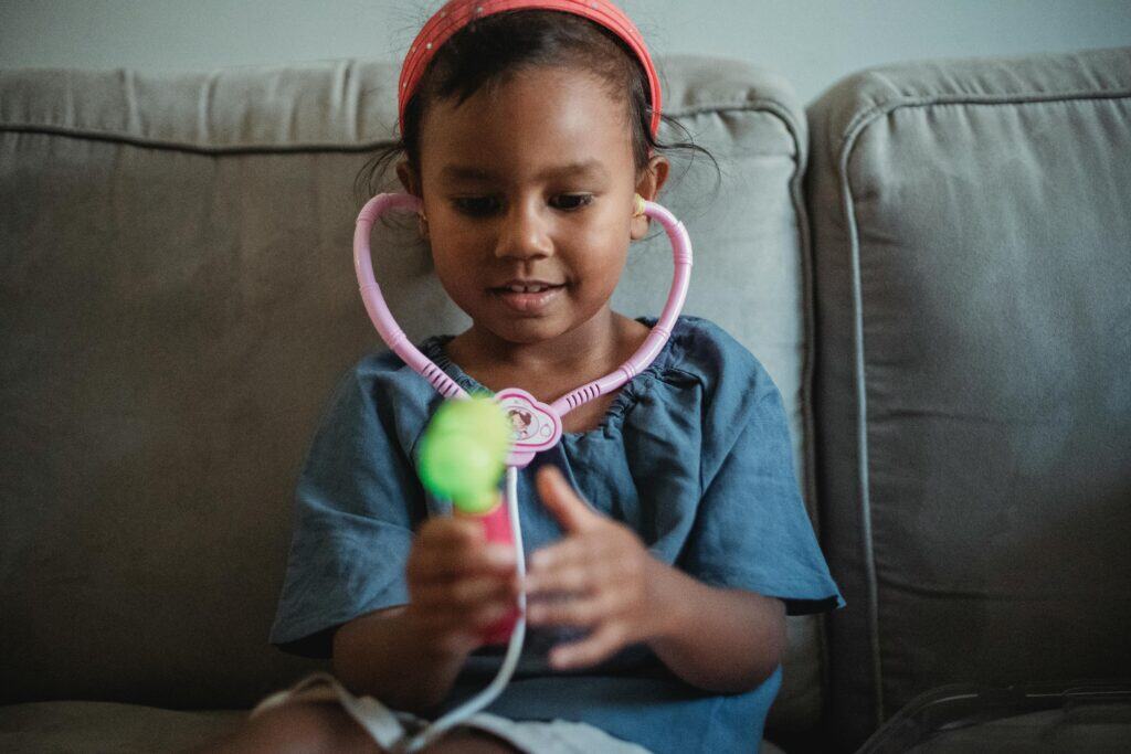 Little girl with play stethoscope on couch