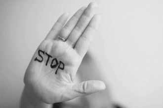 A hand held up in a stop gesture with the word “STOP” written on the palm, symbolizing the importance of setting boundaries to protect against emotional abuse.