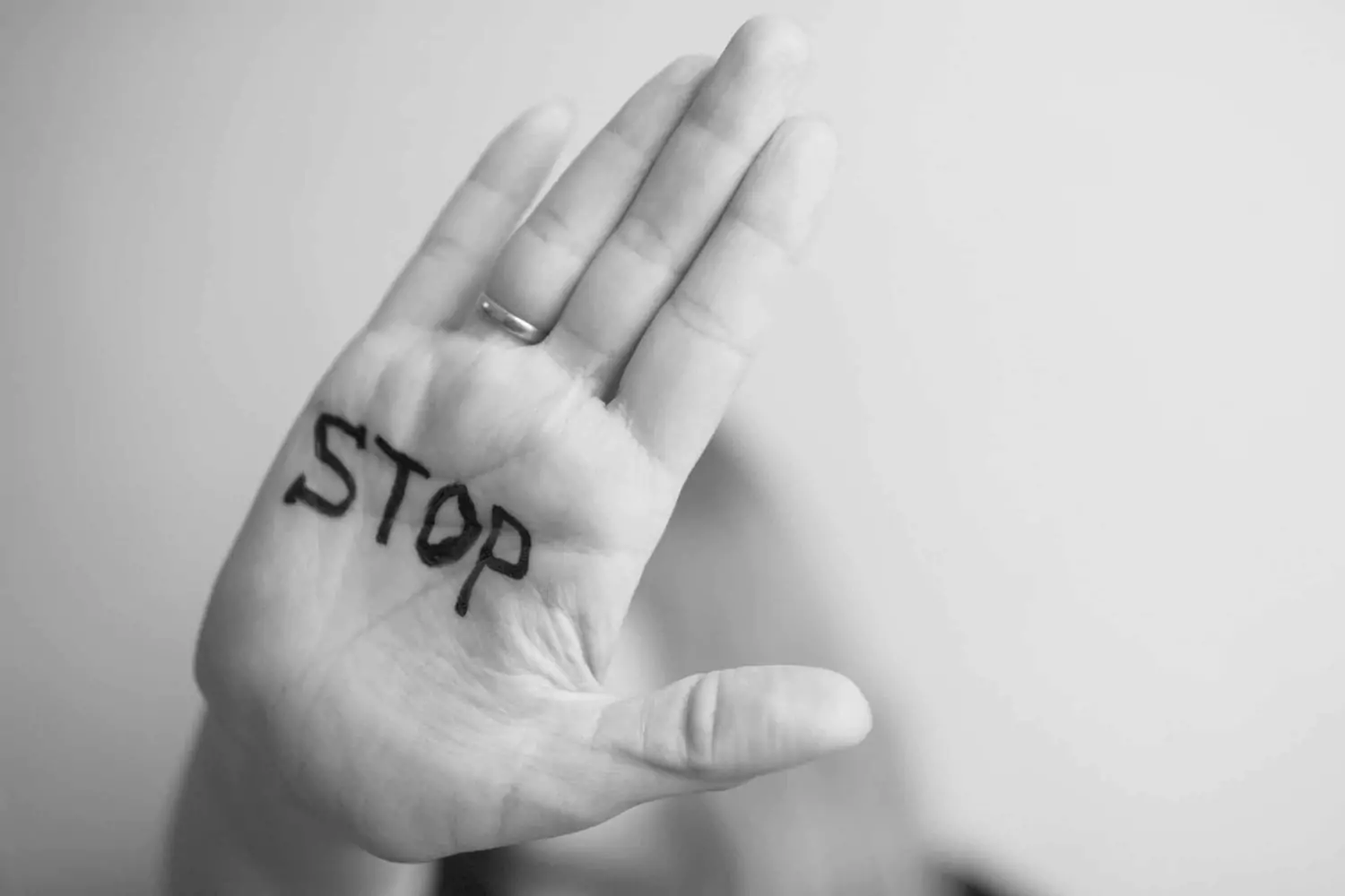 A hand held up in a stop gesture with the word “STOP” written on the palm, symbolizing the importance of setting boundaries to protect against emotional abuse.