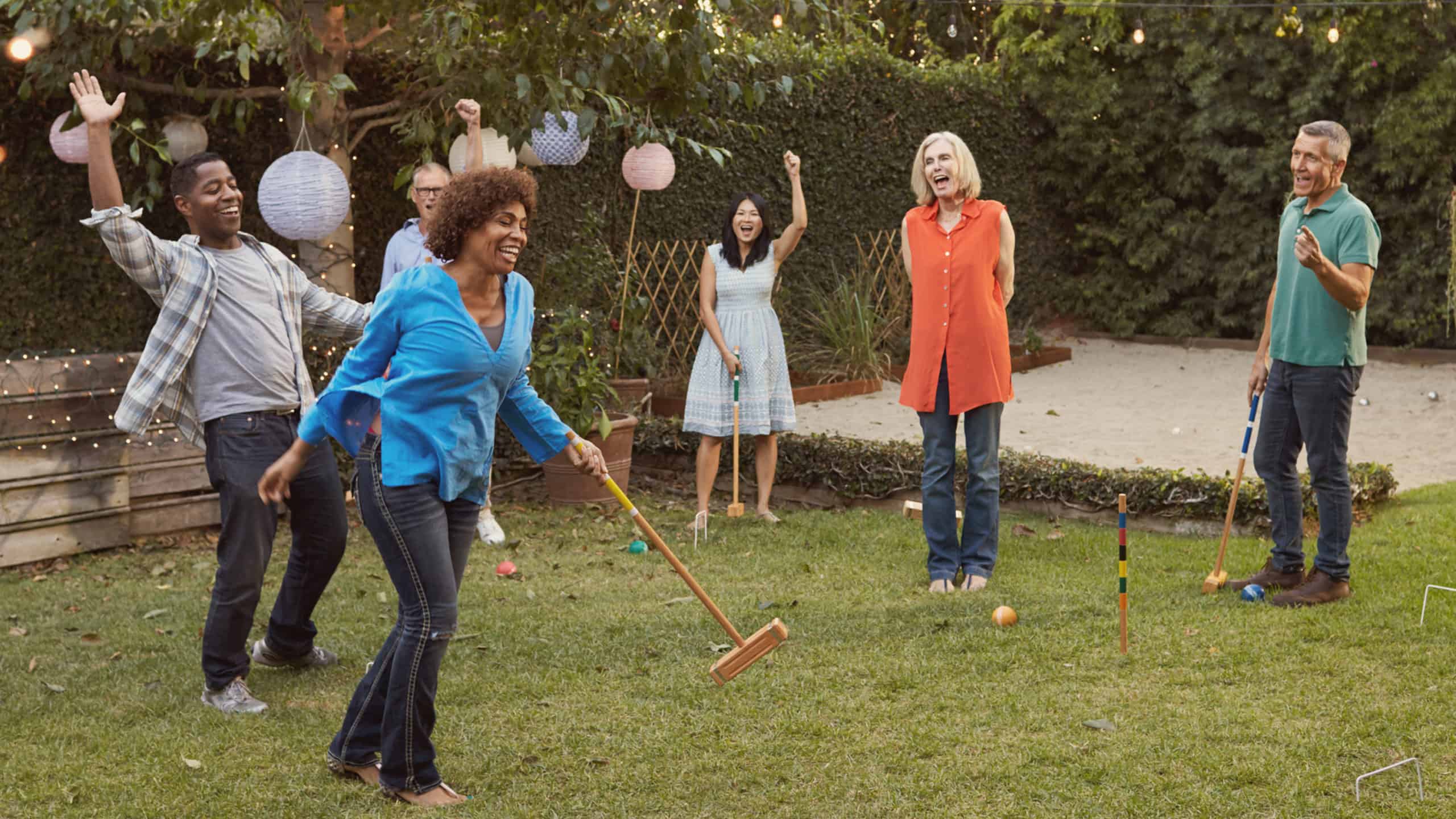 Group Of Mature Friends Playing Croquet In Backyard Together