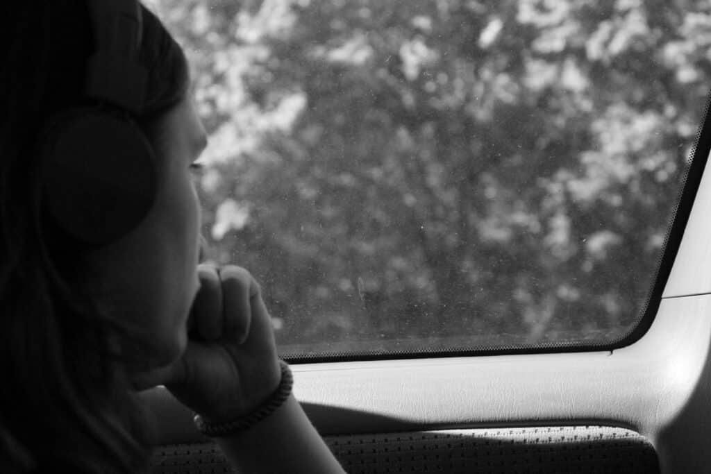 Solemn girl looking out car window. Black and white photo.