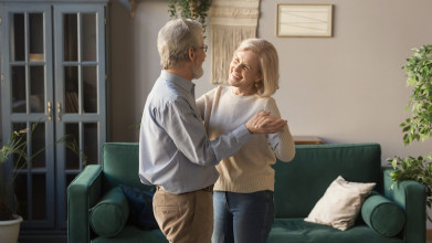 Older couple dancing in living room learning how to live empty nest now that the kids are grown