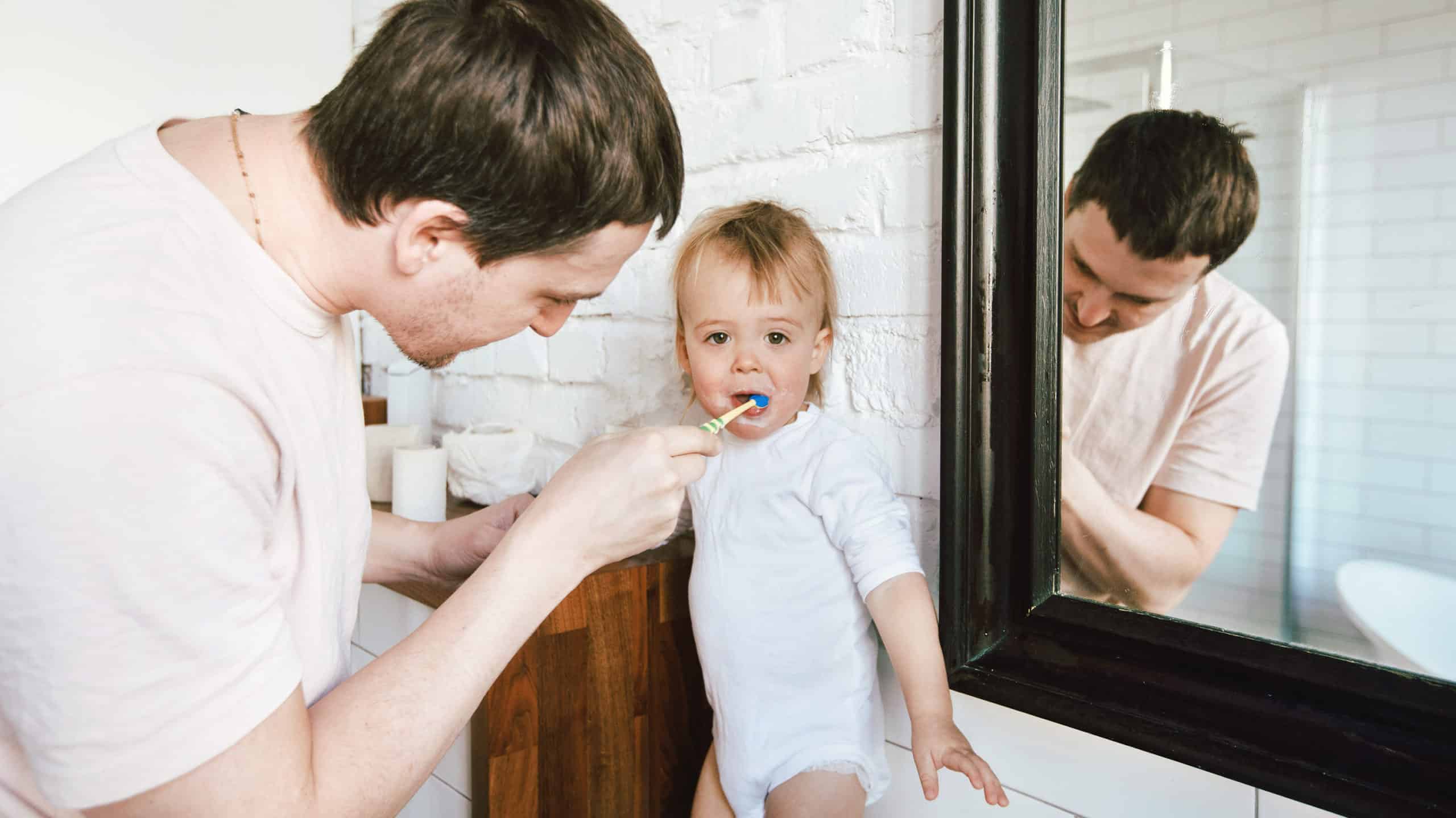 Husband brushing toddler's teeth showing how to love your wife