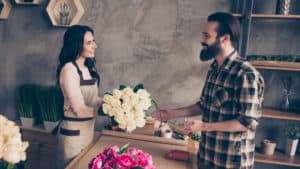 A man buys flowers from a woman in a shop