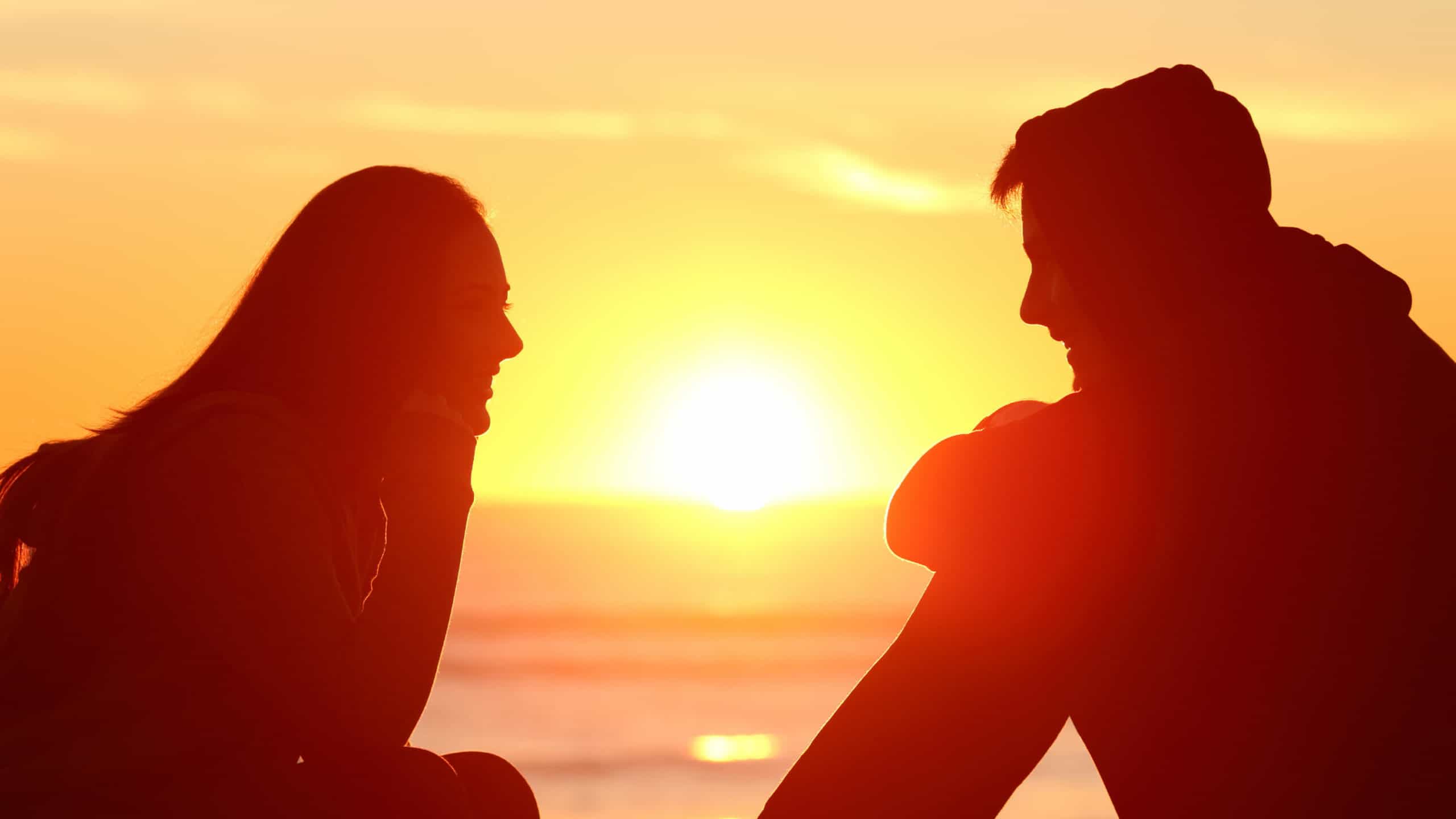 A man and woman enjoy the sunset on a beach