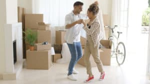 A man and woman dance as they unpack boxes