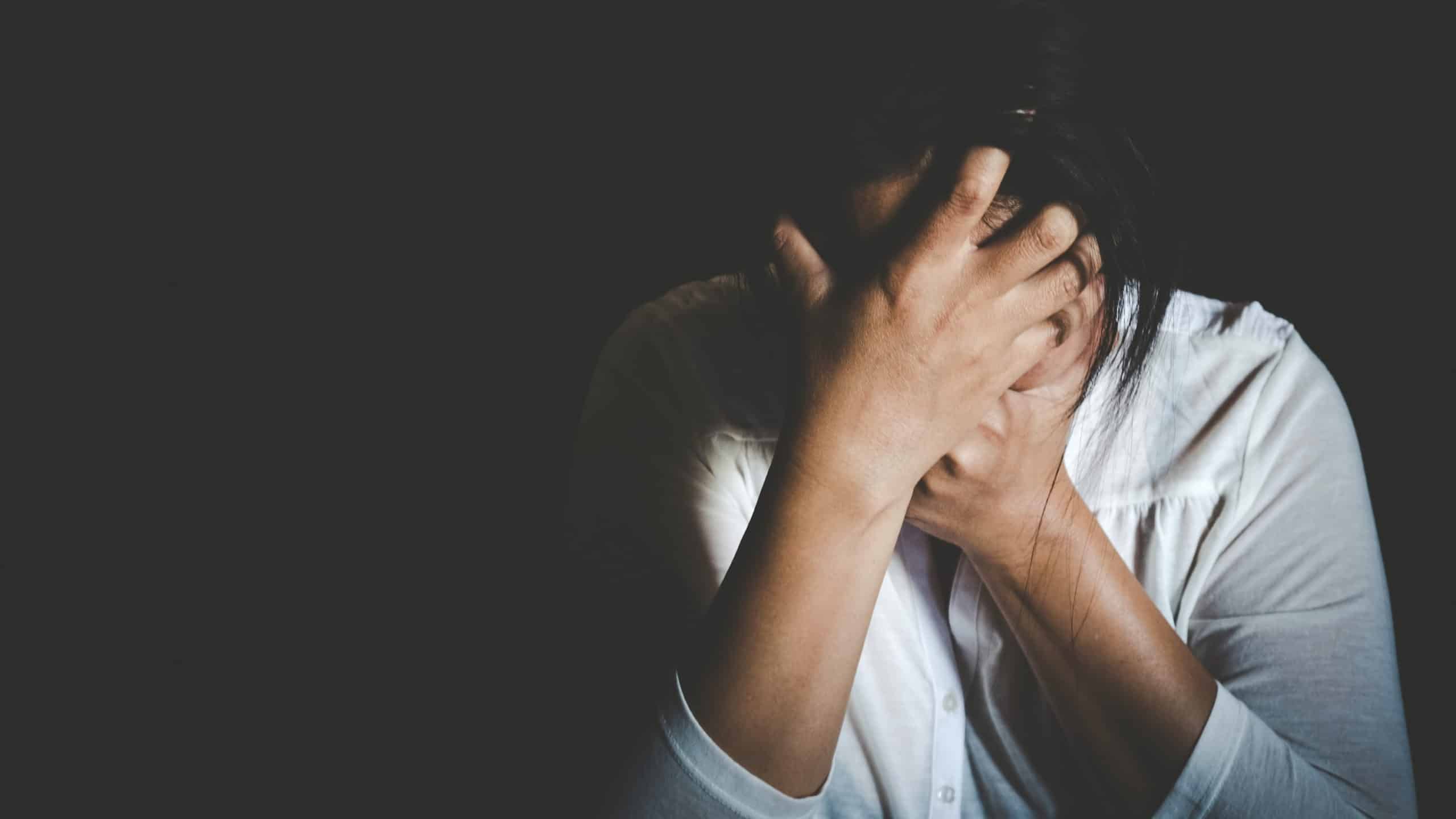 Woman covering her face in protection from harmful relationship