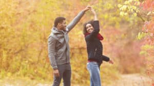 A man and woman dance among autumn leaves