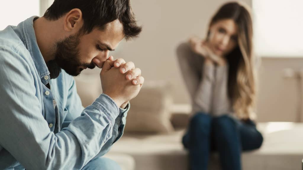 Husband with head in hands processing grieving information and dealing with past abortion in marriage