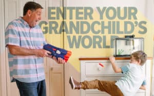 Grandpa shooting toy gun at grandson who’s trying to dodge the foam dart, with the phrase ‘Enter Your Grandchild’s World’